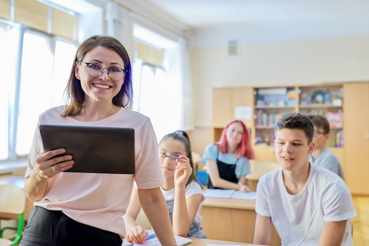 Teacher holding tablet with students