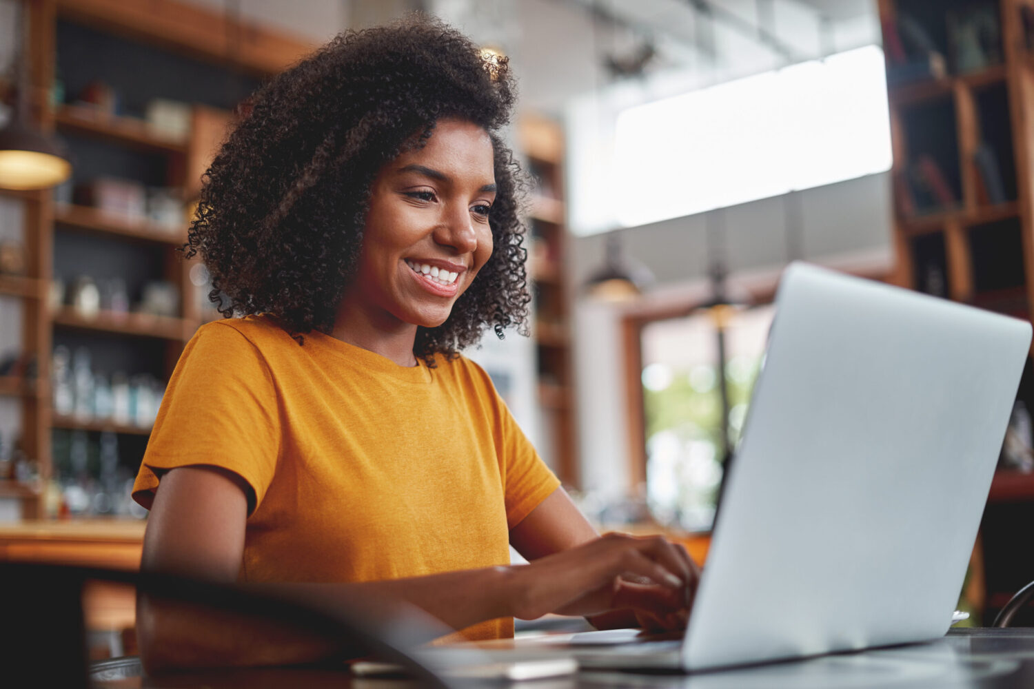 Portrait of an happy young woman enjoying using laptop in cafe