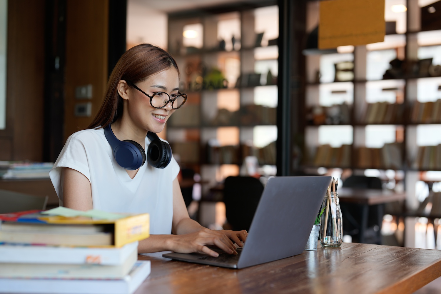 Smiling asian teenage using headset looking at laptop screen listen and learning online courses. Happy chinese business woman with headphones video call. online education concept.