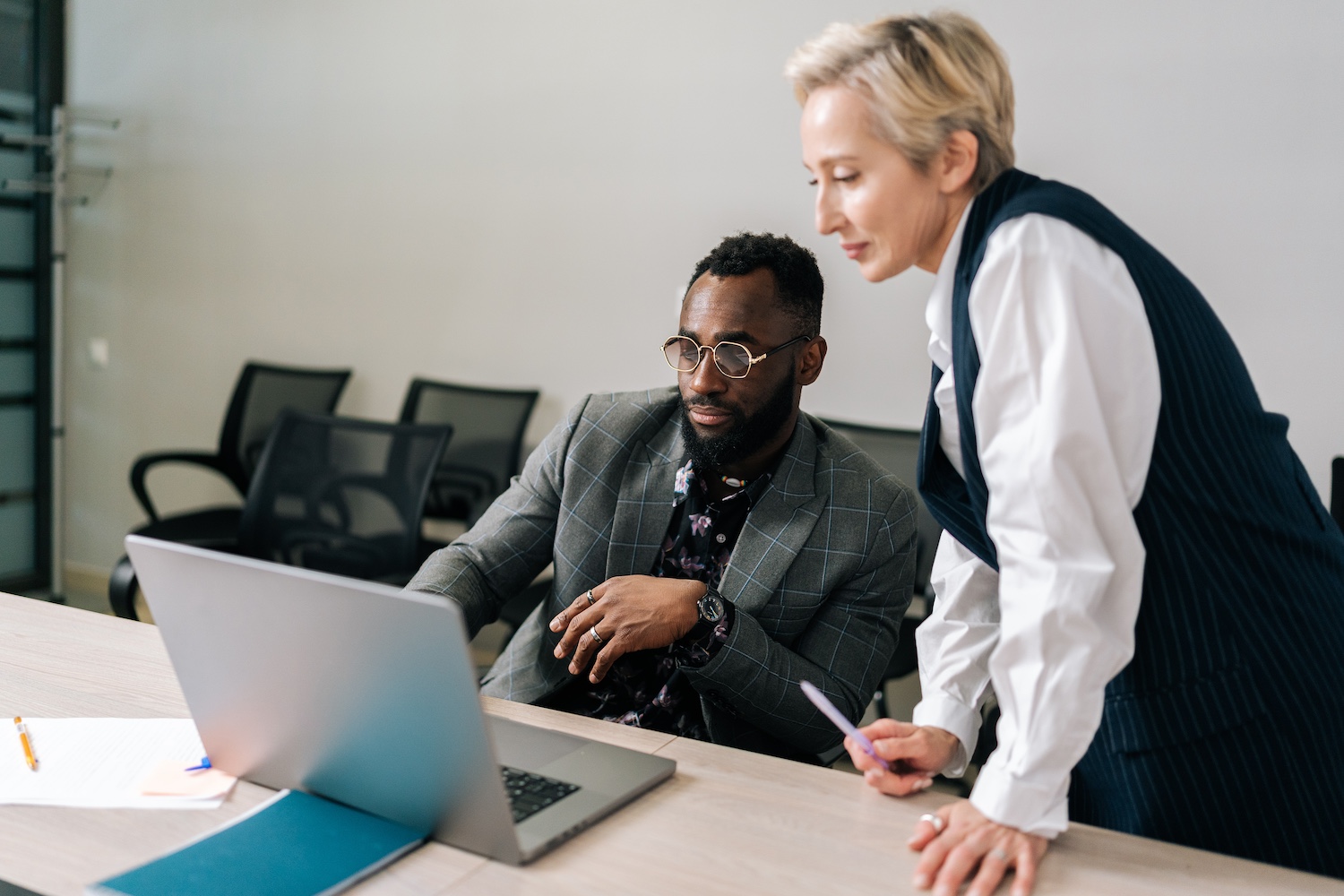 Middle-adult female Caucasian mentor supervisor help male african intern explain computer work corporate software. Businesswoman instruct trainee new worker