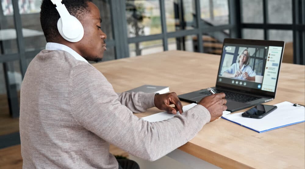 Man wearing headphones working at laptop on desk